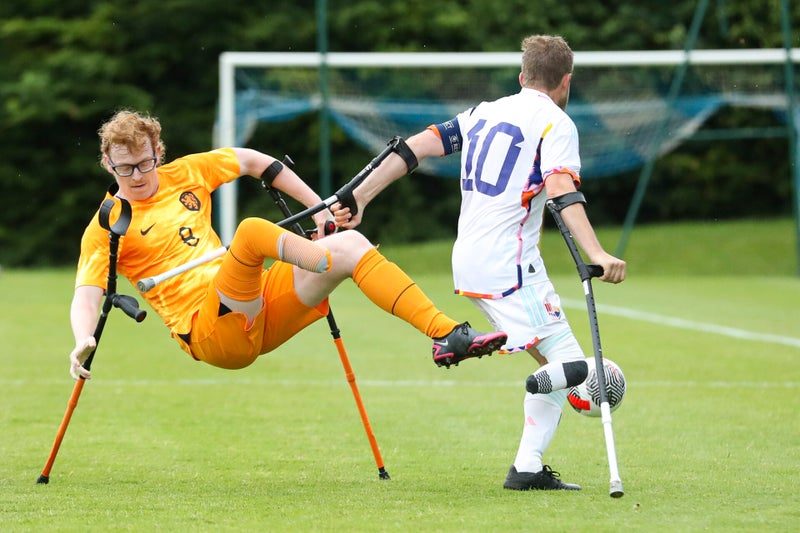 Speler haalt acrobatisch uit voor het doel, de keeper kijkt toe