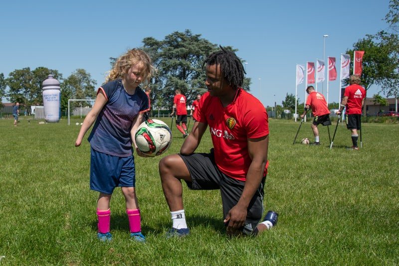 Een speler speelt de bal over naar een kind op het gras